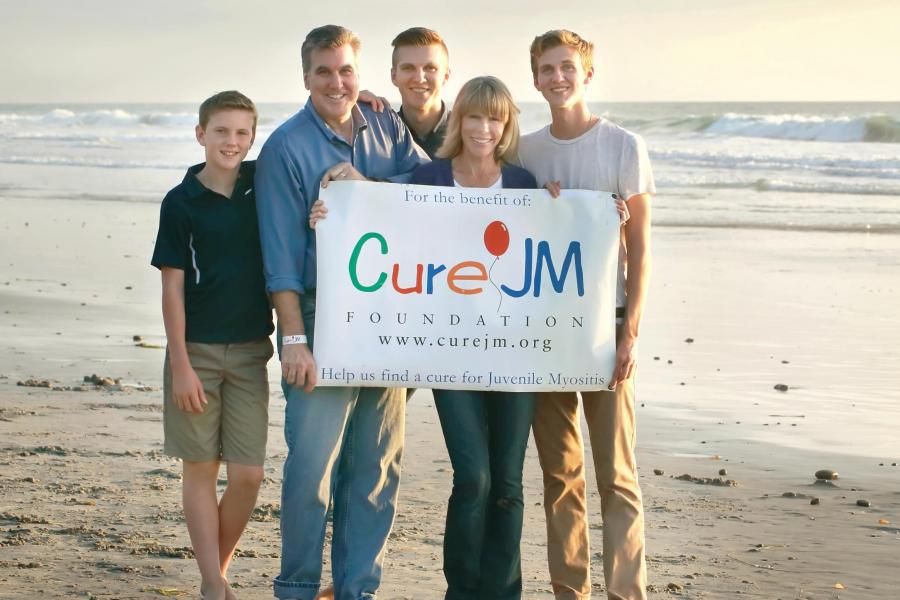 Una familia sostiene un cartel de Cure JM en una playa