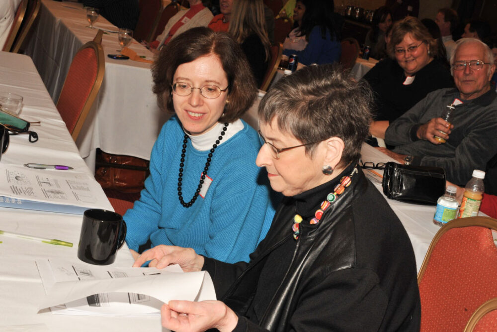 Dos mujeres leyendo notas en una conferencia.