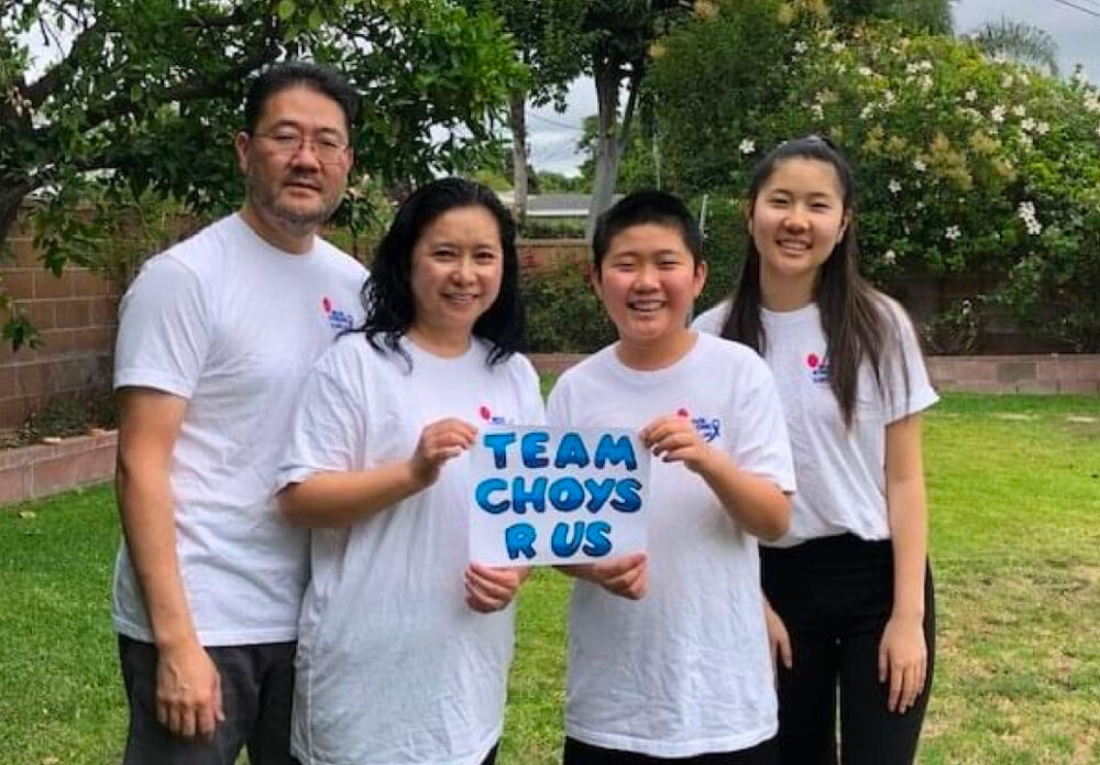 Familia sonriente con el cartel "Team Choys R Us